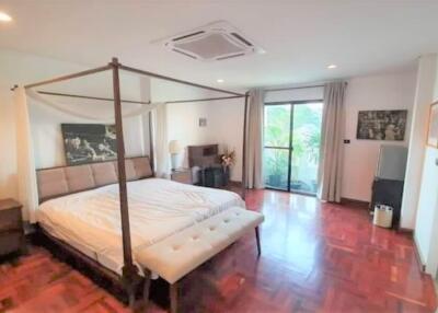 Spacious bedroom with a four-poster bed, wooden floors, and large windows