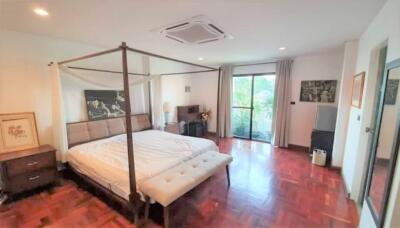 Spacious bedroom with a four-poster bed, wooden floors, and large windows