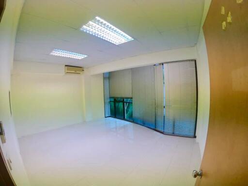 Spacious empty room with large windows and blinds, white tiles, air conditioning, and ceiling lights