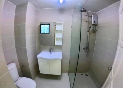 Modern bathroom with tiled walls, a vanity, a toilet, and a glass shower enclosure