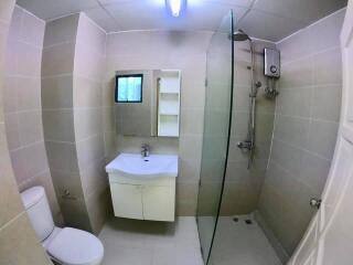 Modern bathroom with tiled walls, a vanity, a toilet, and a glass shower enclosure