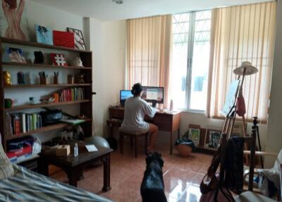 Person working at desk in room with shelves and dog