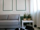 Small living room with a grey sofa and a white side table with potted plants