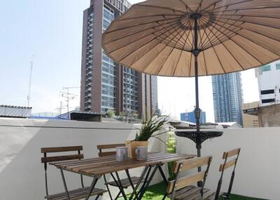 Outdoor dining area with table and chairs under an umbrella on an artificial grass surface