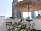 Outdoor dining area with table and chairs under an umbrella on an artificial grass surface