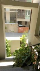 View of an apartment building entrance with plants and railing