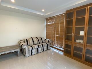 Living room with a striped sofa, glass cabinet, and a wooden table