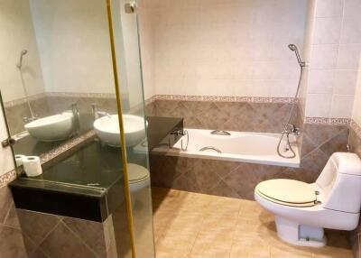 Modern bathroom with tiled walls, glass shower, bathtub, and toilet.