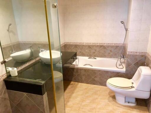 Modern bathroom with tiled walls, glass shower, bathtub, and toilet.