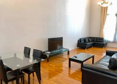 Spacious modern living room with hardwood floors, black leather furniture, and a glass dining table