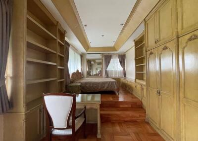 Spacious bedroom with built-in wooden wardrobes and shelves, large bed, and a study desk with a chair