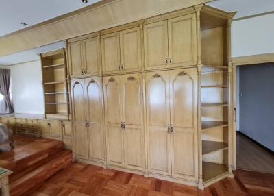 Spacious bedroom with built-in wooden shelving and cabinets