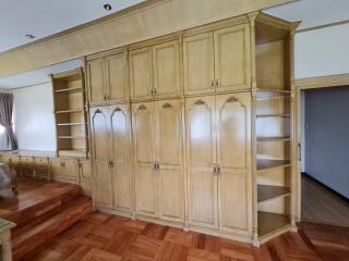 Spacious bedroom with built-in wooden shelving and cabinets