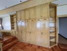 Spacious bedroom with built-in wooden shelving and cabinets