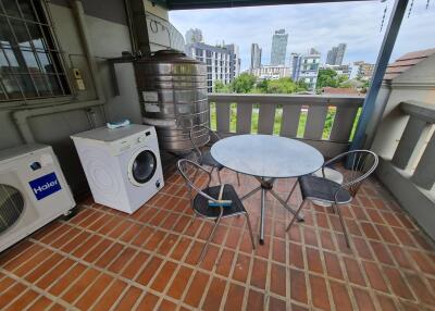 Outdoor balcony with a table, chairs, and a washing machine