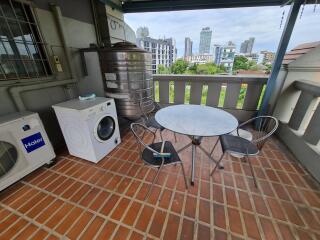 Outdoor balcony with a table, chairs, and a washing machine