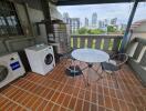 Outdoor balcony with a table, chairs, and a washing machine