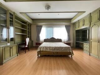 Spacious bedroom with green wooden furniture and large window