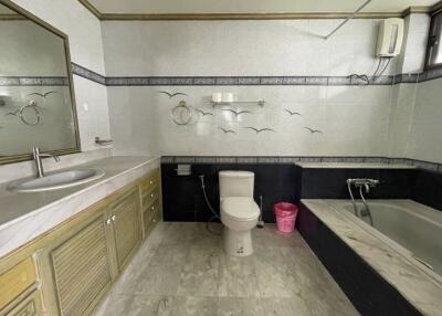 Spacious bathroom with bathtub, sink, toilet, and decorative wall tiles