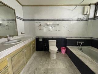 Spacious bathroom with bathtub, sink, toilet, and decorative wall tiles