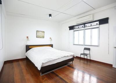 Spacious bedroom with wooden flooring and natural light