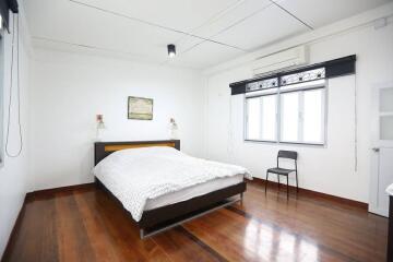 Spacious bedroom with wooden flooring and natural light