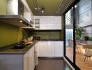 Modern kitchen with green walls, white cabinetry, and outdoor view