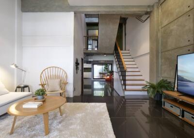 A modern living area featuring a staircase, comfortable seating, and natural lighting