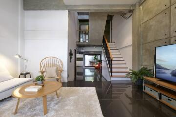 A modern living area featuring a staircase, comfortable seating, and natural lighting