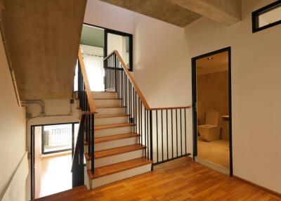 Staircase with wooden steps and black railings leading to upper floor, adjacent to a room with an open door