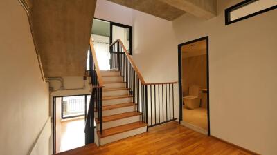 Staircase with wooden steps and black railings leading to upper floor, adjacent to a room with an open door