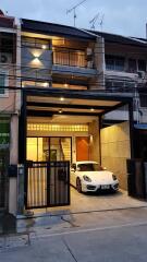 Three-story building with a garage and a white car parked in front