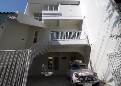 Three-story building exterior with car parked in driveway