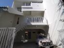 Three-story building exterior with car parked in driveway