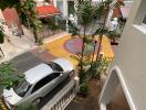 View from balcony overlooking street with parked luxury car and decorative courtyard