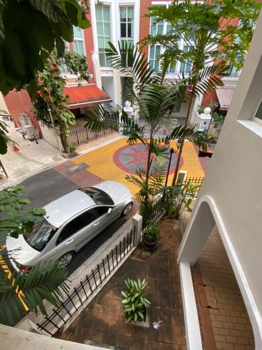 View from balcony overlooking street with parked luxury car and decorative courtyard