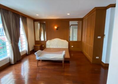 Spacious bedroom with large windows, hardwood floor, and built-in wardrobe