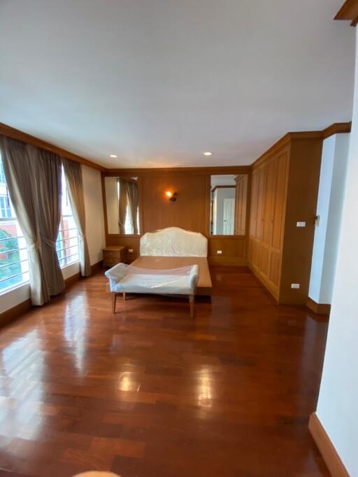 Spacious bedroom with large windows, hardwood floor, and built-in wardrobe