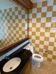 Bathroom with large mirror, granite countertop, sink, toilet, and tiled walls