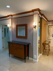 A stylishly decorated interior living space with a sideboard, wall mirror, lighting sconces, and French doors.