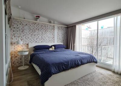 Modern bedroom with a large window and exposed brick wall