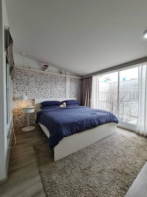 Modern bedroom with a large window and exposed brick wall