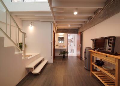 Modern hallway with staircase leading to upper floor, connected to a small kitchenette and bathroom.