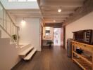 Modern hallway with staircase leading to upper floor, connected to a small kitchenette and bathroom.