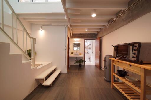 Modern hallway with staircase leading to upper floor, connected to a small kitchenette and bathroom.