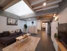 Modern living room with skylight, grey sofa, wooden furniture, and wall-mounted TV.