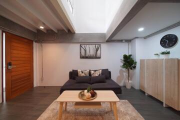 Modern living room with a gray sofa, wooden coffee table, and indoor plants