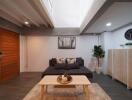 Modern living room with a gray sofa, wooden coffee table, and indoor plants