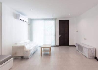 Minimalist living room with white sofa, air conditioner, coffee table, and floor-to-ceiling window with blinds