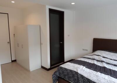 Modern bedroom with white walls, wardrobe, and bed with striped bedding